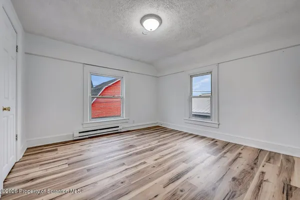 a view of an empty room with window and wooden floor