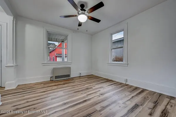 a view of an empty room with window and wooden floor