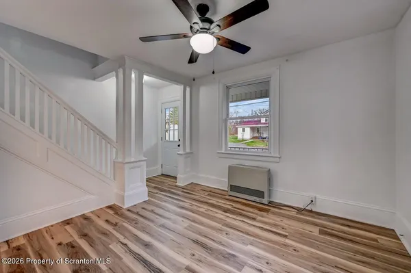 a view of an empty room with wooden floor and a window