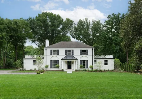 a view of a yard in front of a house with plants and large tree