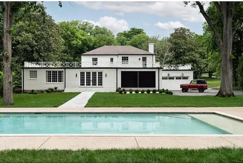 a view of a white house next to a yard and large trees
