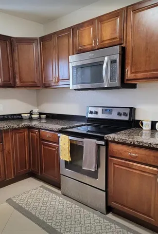 a kitchen with granite countertop wood cabinets stainless steel appliances and a sink