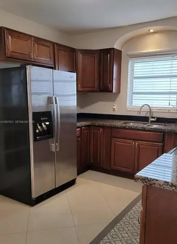 a kitchen with stainless steel appliances granite countertop a refrigerator a sink and wooden cabinets