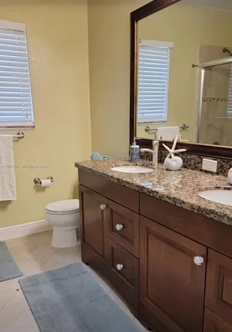 a bathroom with a granite countertop sink toilet and mirror