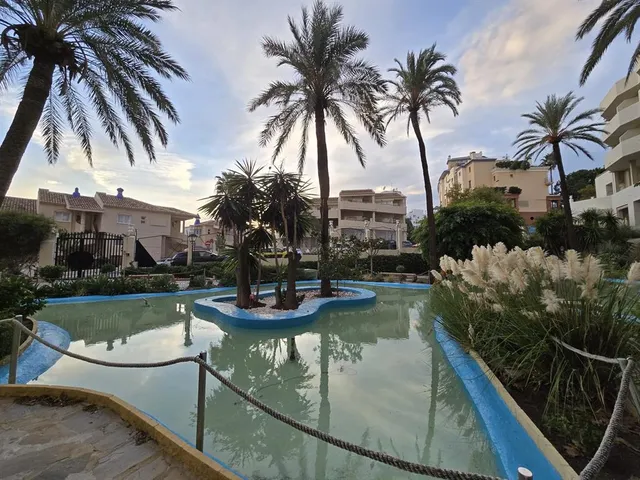 a view of a swimming pool with lawn chairs and iron fence