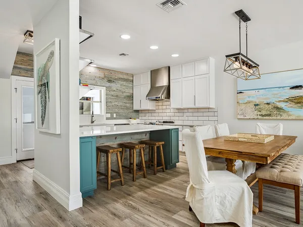 a kitchen with stainless steel appliances kitchen island granite countertop a table chairs sink and cabinets