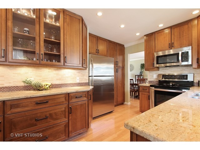910 Dannet Road Buffalo Grove, IL 60089 - Photo 6 of 25 a kitchen with granite countertop wooden cabinets a refrigerator and a sink