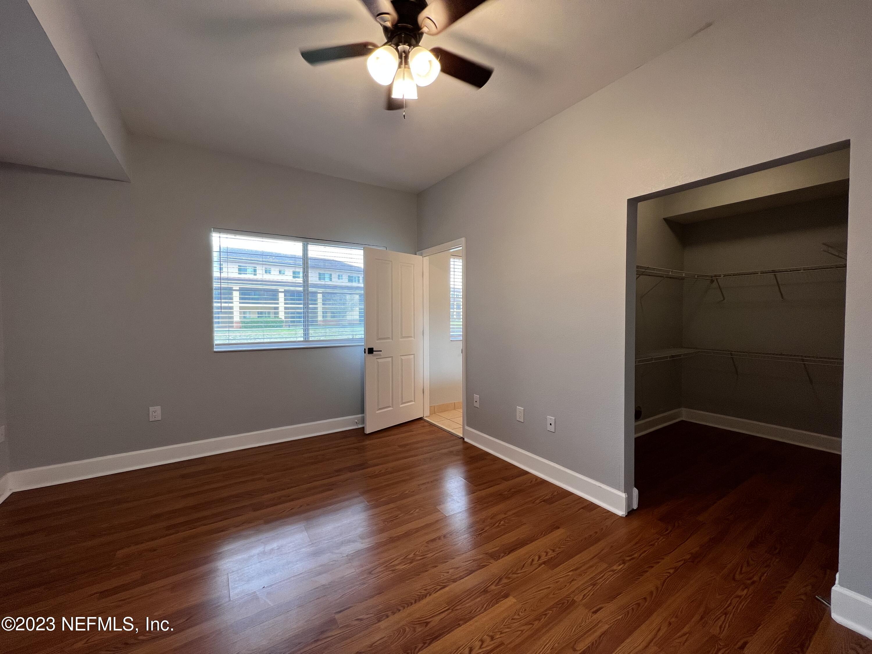 9745 Touchton Road, Unit 1702 Jacksonville, FL 32246 - Photo 26 of 62 an empty room with wooden floor chandelier fan and windows