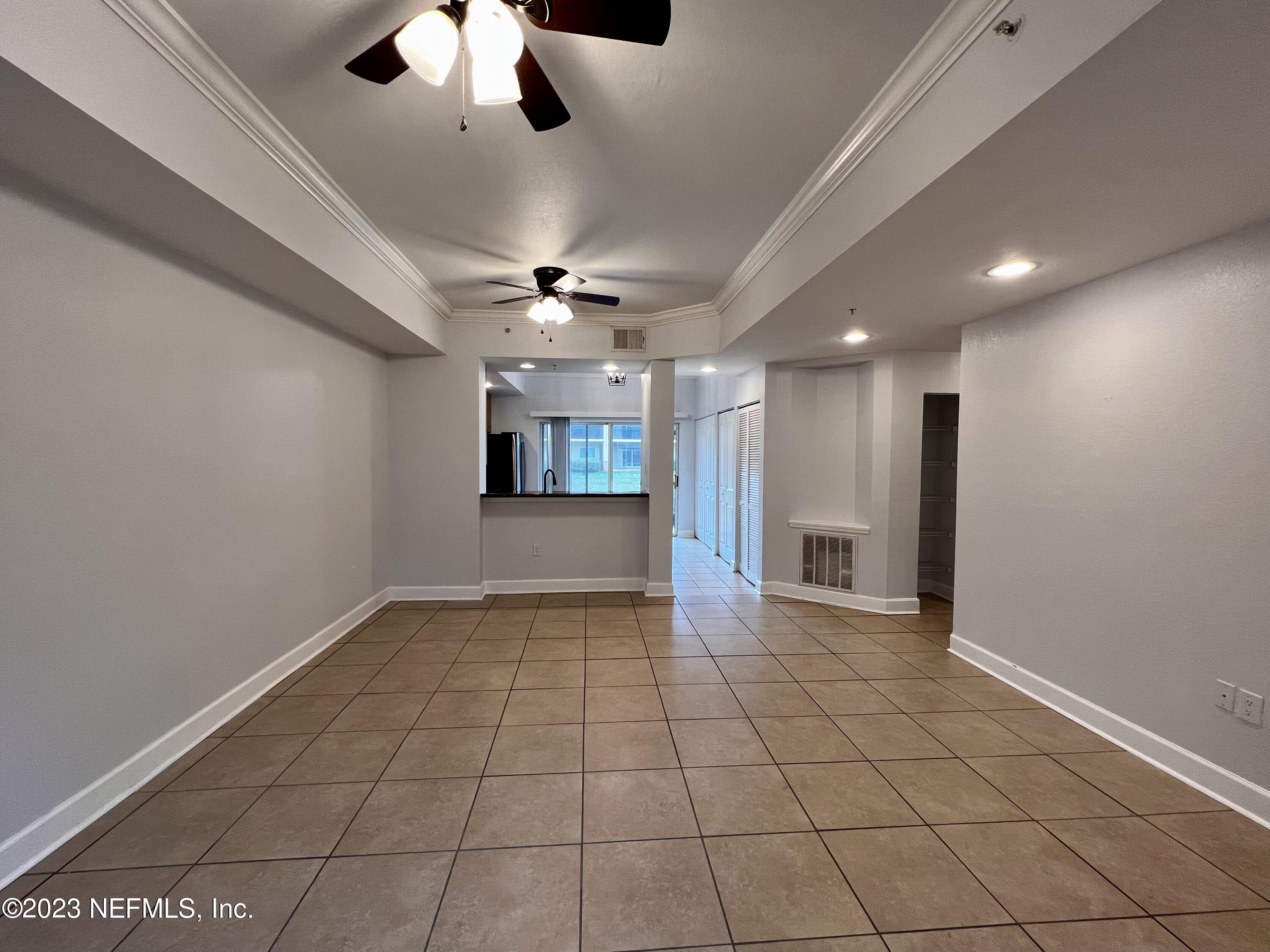 9745 Touchton Road, Unit 1702 Jacksonville, FL 32246 - Photo 8 of 62 a view of an empty room with a chandelier fan and kitchen view