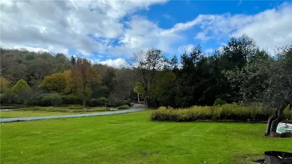 a view of a big house with a big yard and large trees
