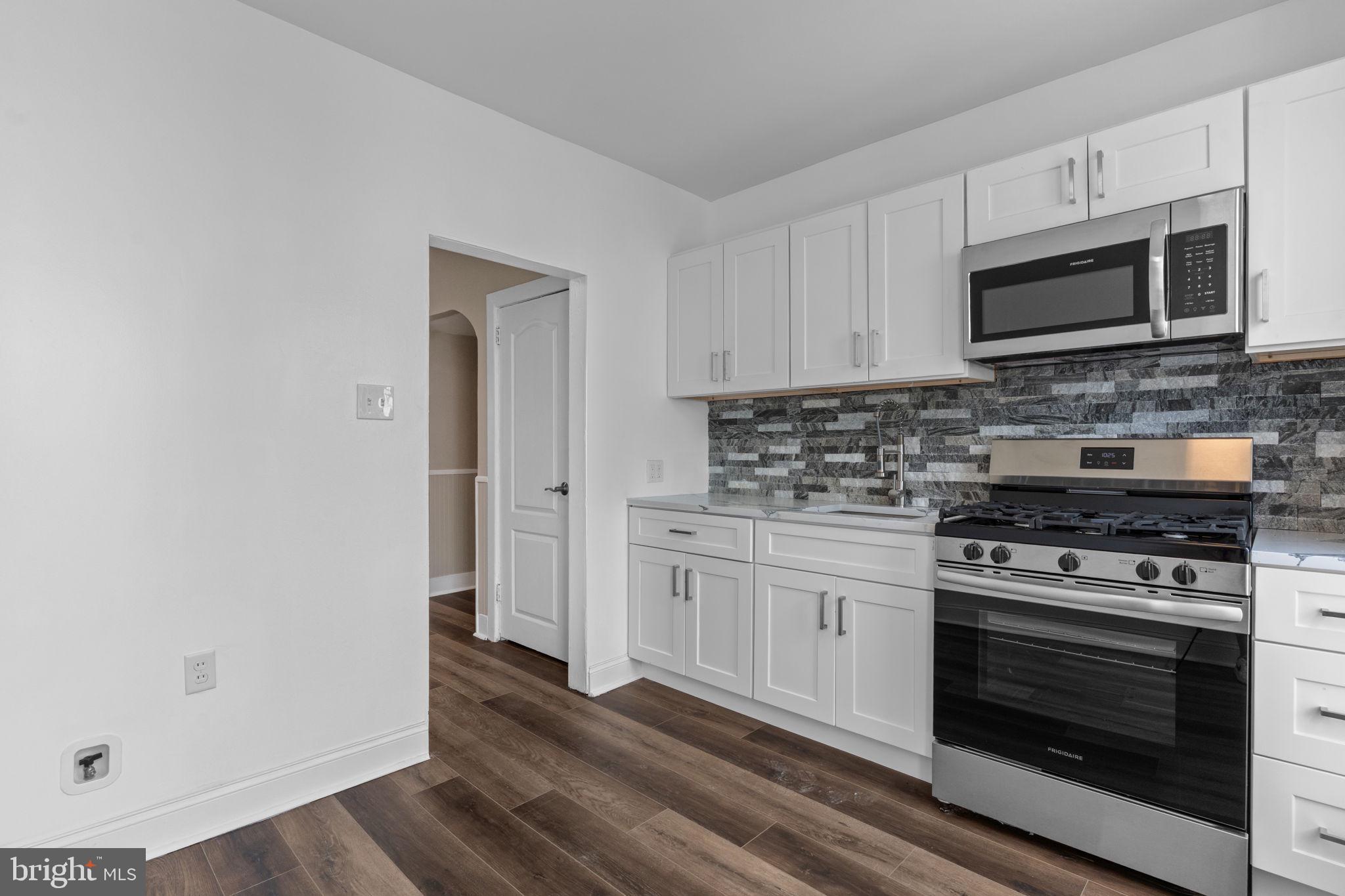 7122 Gillespie Street Philadelphia, PA 19135 - Photo 8 of 24 a kitchen with stainless steel appliances granite countertop a stove microwave and sink