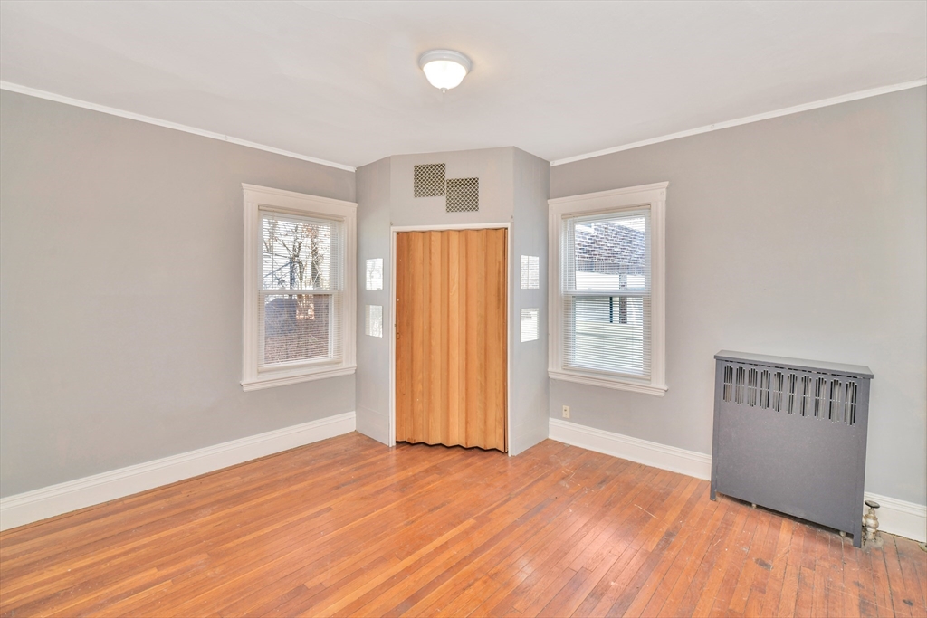 146 Homestead Street Boston, MA 02121 - Photo 15 of 40 an empty room with wooden floor and windows