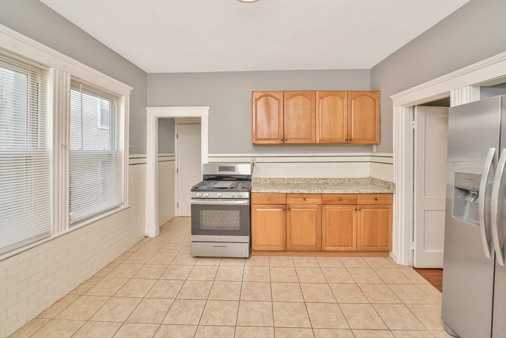 146 Homestead Street Boston, MA 02121 - Photo 8 of 40 a kitchen with granite countertop a refrigerator and a stove top oven