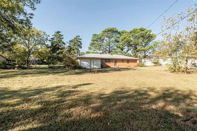 a view of house with yard and trees in the background