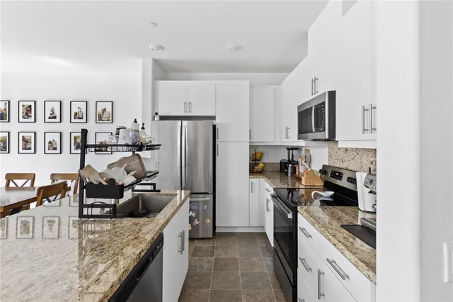 a kitchen with stainless steel appliances granite countertop a sink and a refrigerator