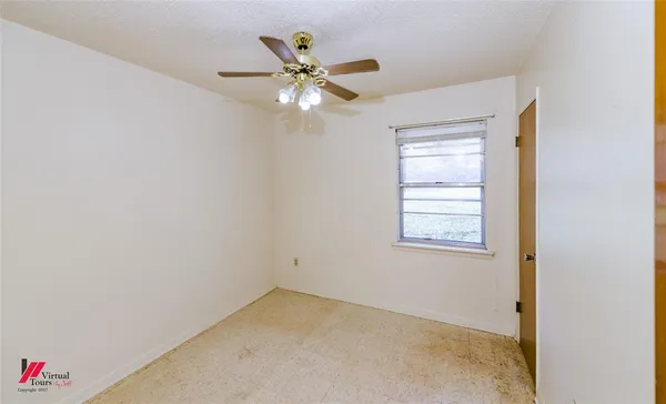 an empty room with a window and a fan