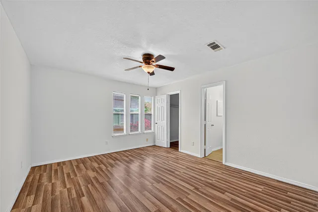 a view of empty room with wooden floor and fan