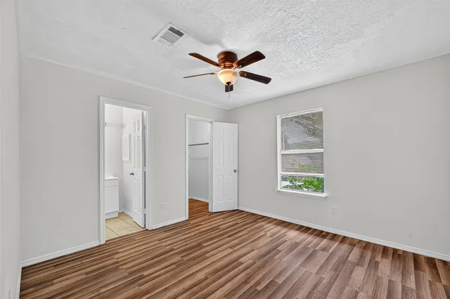 a view of empty room with wooden floor and fan