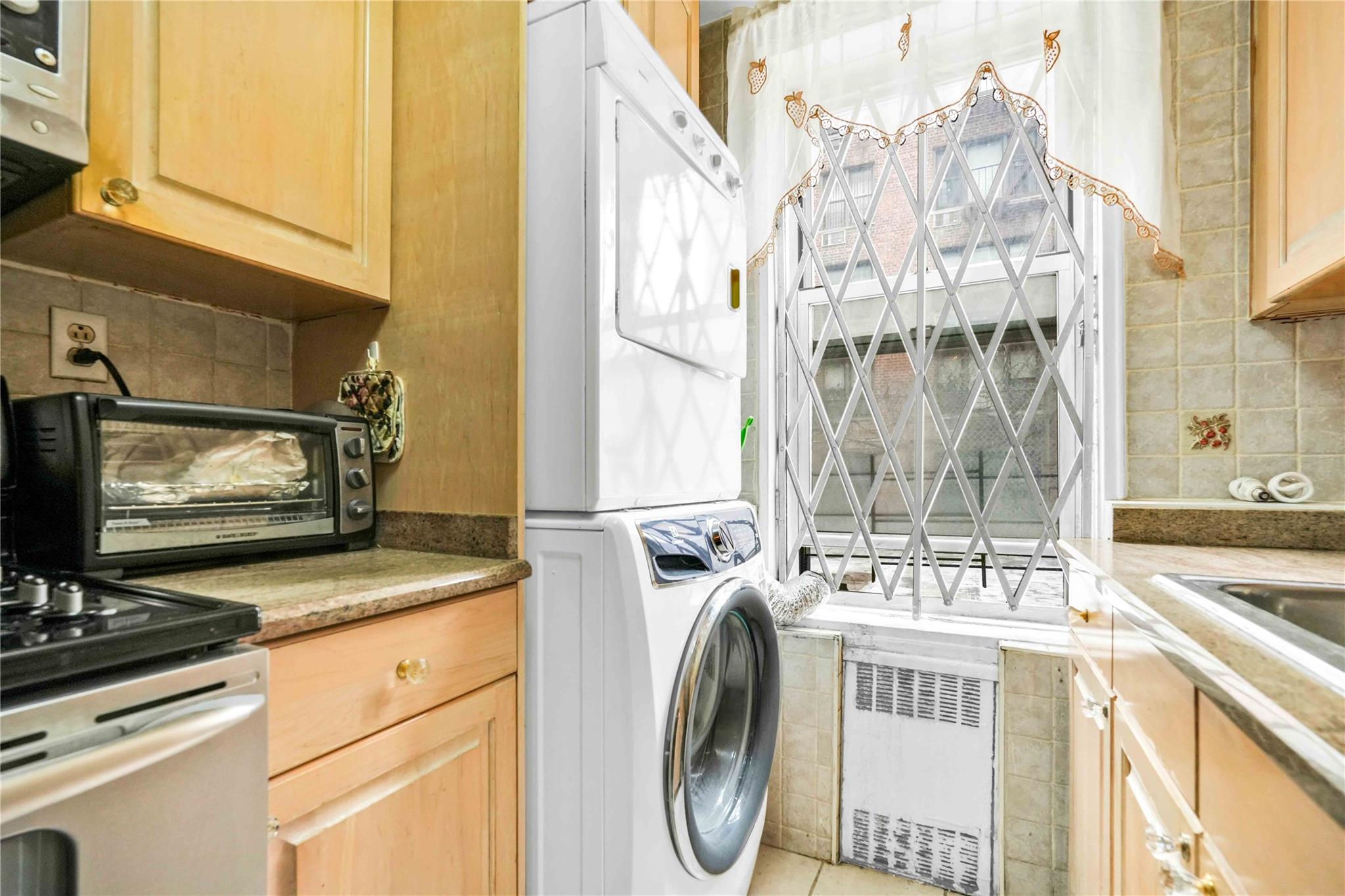 42-25 80th Street, Unit 1F Queens, NY 11373 - Photo 16 of 27 Washroom with stacked washer / dryer, tile patterned floors, laundry area, and a toaster