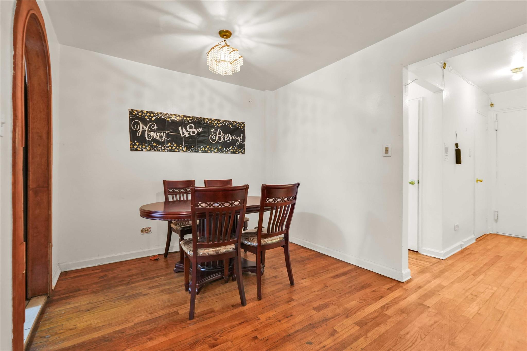42-25 80th Street, Unit 1F Queens, NY 11373 - Photo 10 of 27 Dining space featuring baseboards, an inviting chandelier, and hardwood / wood-style flooring