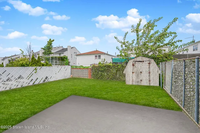 a view of a back yard with flower plants and wooden fence