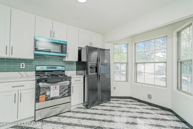 a kitchen with stainless steel appliances granite countertop a stove a refrigerator and a stove top oven