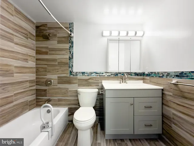 a bathroom with a granite countertop sink toilet and mirror