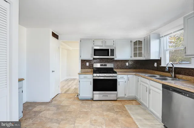 a large kitchen with cabinets stainless steel appliances and a window