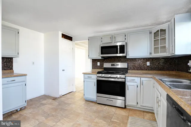 a kitchen with granite countertop a stove a microwave a sink and cabinets