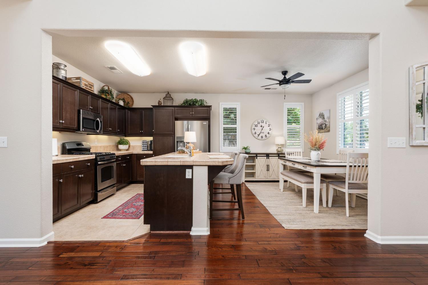 3942 Harlan Ranch Boulevard Clovis, CA 93619 - Photo 3 of 21 a kitchen with stainless steel appliances kitchen island granite countertop a stove top oven a sink a dining table and chairs