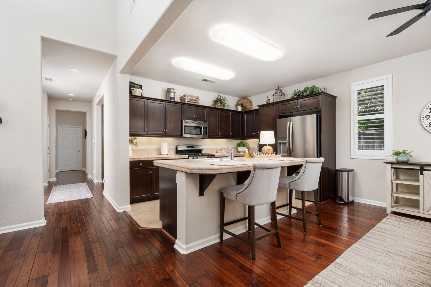 3942 Harlan Ranch Boulevard Clovis, CA 93619 - Photo 4 of 21 a kitchen with stainless steel appliances kitchen island granite countertop a table chairs sink refrigerator and cabinets