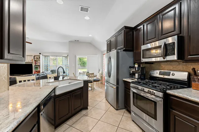 a kitchen with stainless steel appliances granite countertop a stove refrigerator sink and microwave