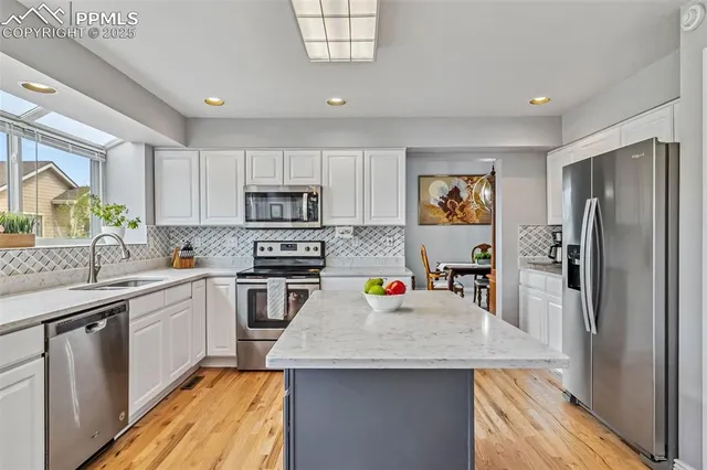 a kitchen with a sink a center island stainless steel appliances cabinets and a window