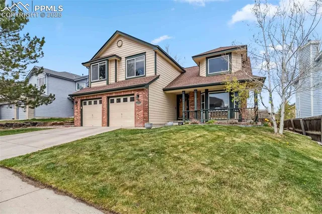 a front view of a house with a garden and trees