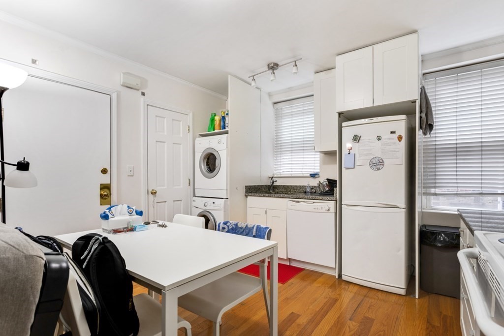 72 North Margin Street Boston, MA 02113 - Photo 31 of 42 a white kitchen with a refrigerator a stove a sink dishwasher a dining table and chairs with wooden floor