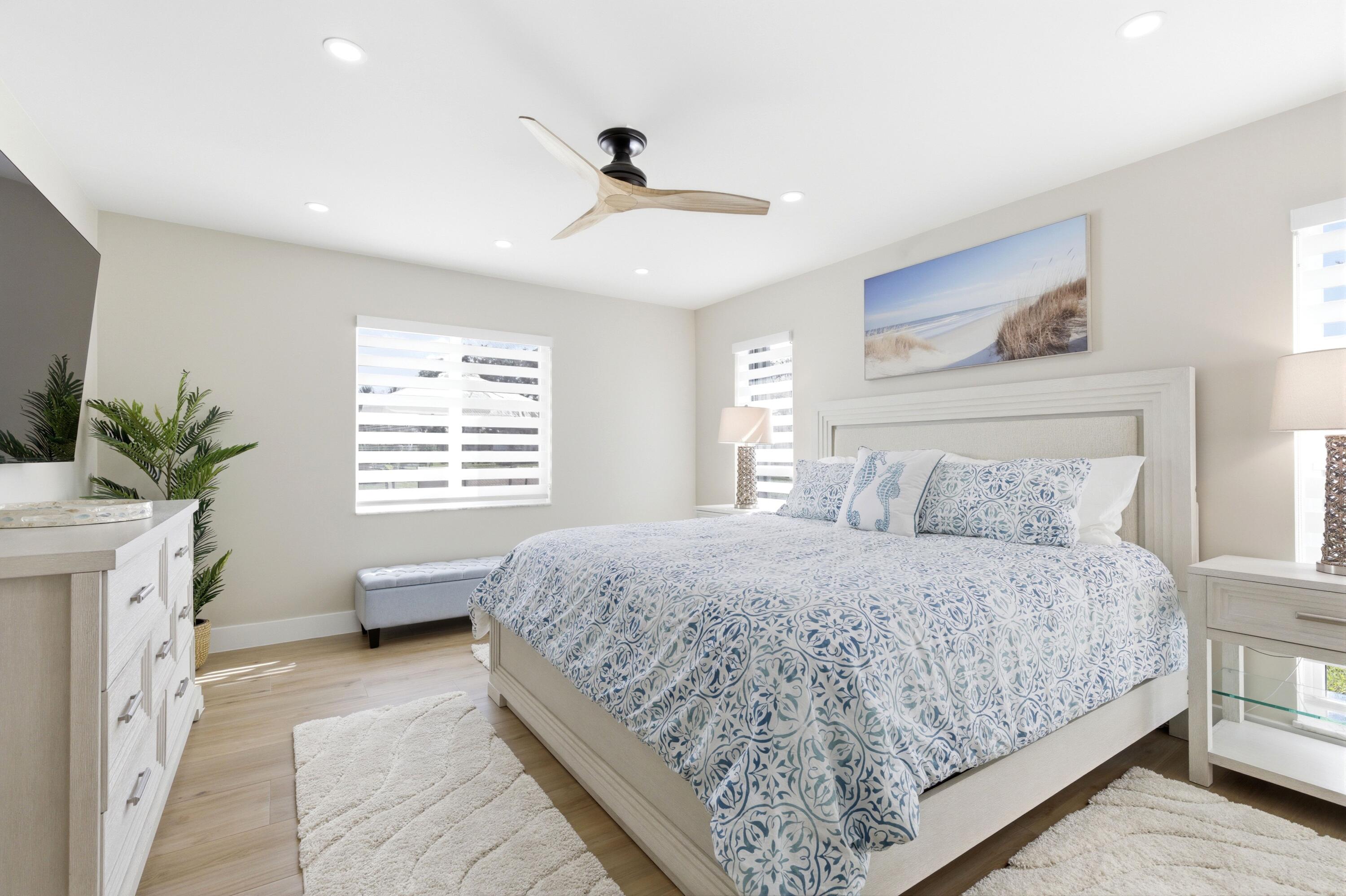 1415 Southwest 27th Avenue, Unit 104 Delray Beach, FL 33445 - Photo 20 of 43 a bedroom with a large bed and a chandelier