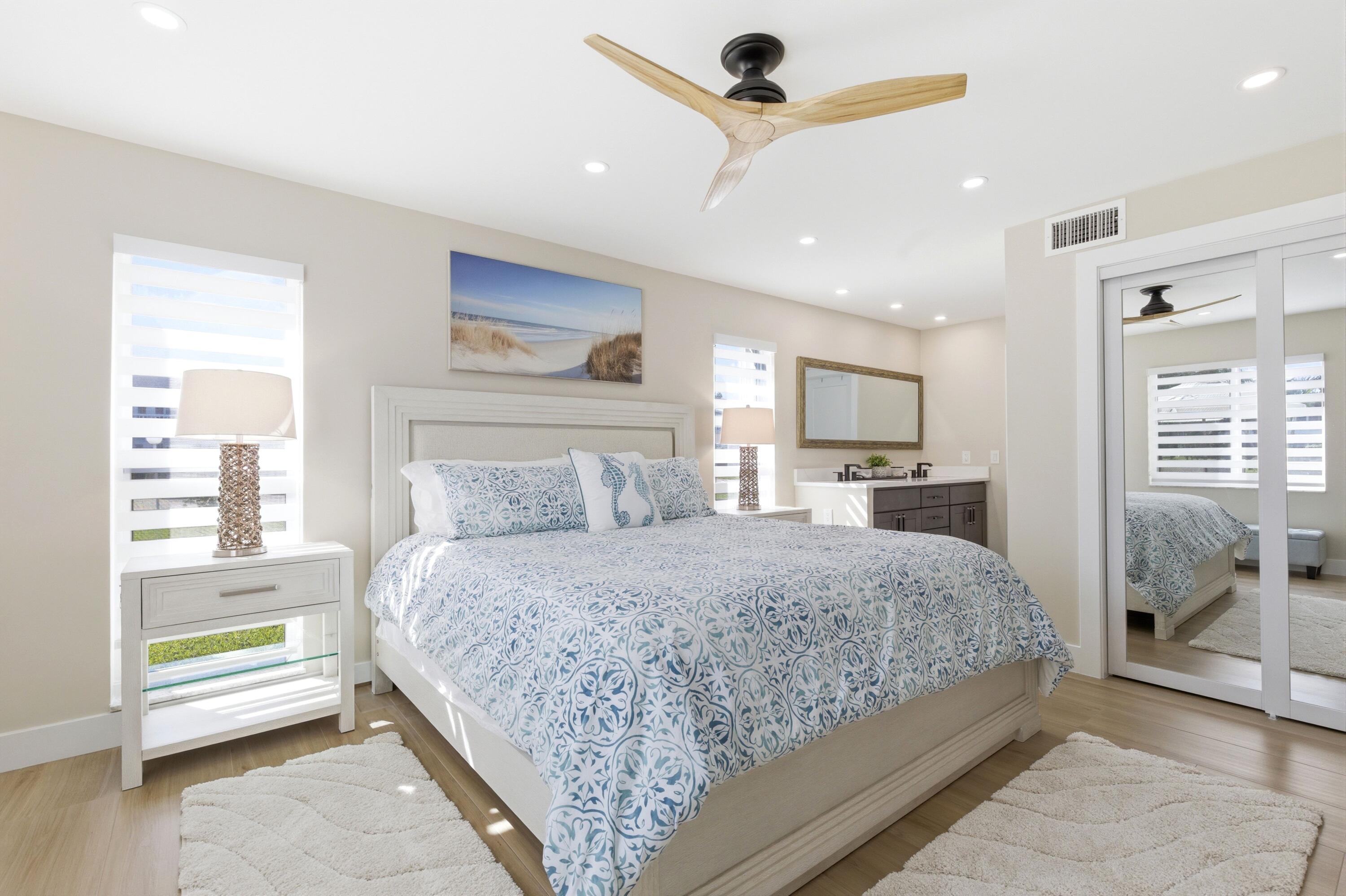 1415 Southwest 27th Avenue, Unit 104 Delray Beach, FL 33445 - Photo 22 of 43 a bedroom with a large bed and a chandelier