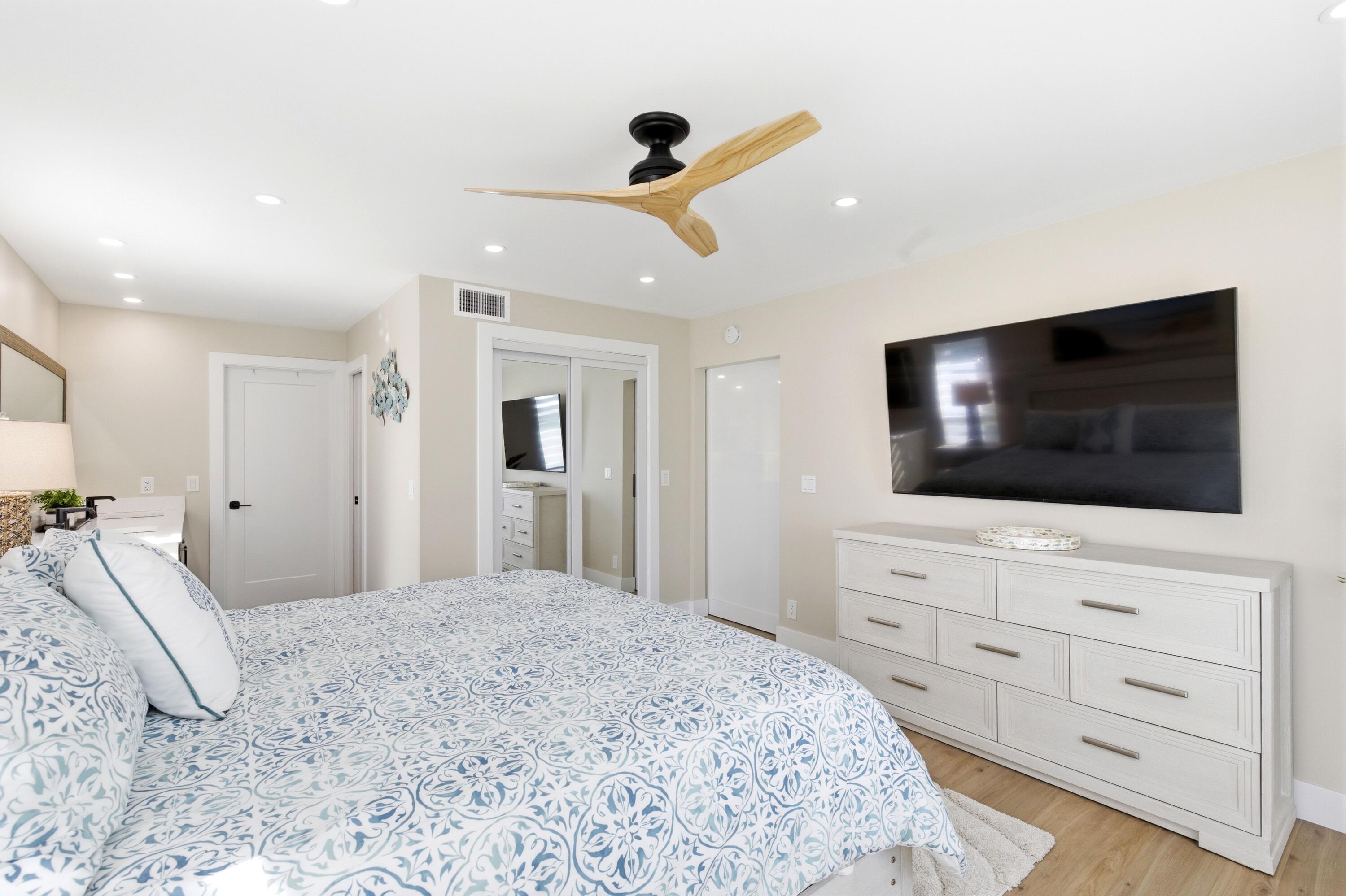 1415 Southwest 27th Avenue, Unit 104 Delray Beach, FL 33445 - Photo 23 of 43 a bedroom with a bed and a flat screen tv in white walls