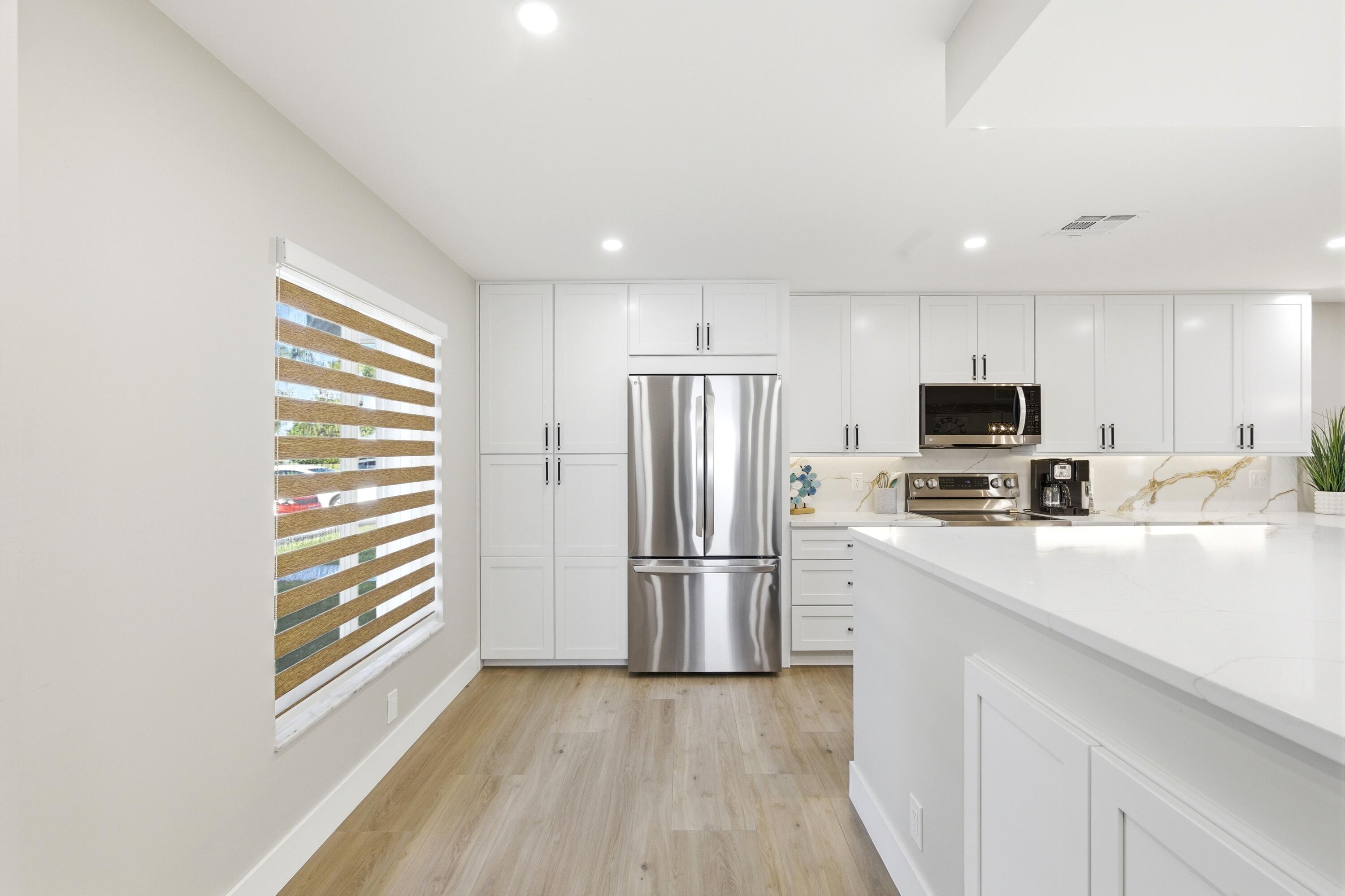 1415 Southwest 27th Avenue, Unit 104 Delray Beach, FL 33445 - Photo 3 of 43 a kitchen with stainless steel appliances a refrigerator sink and microwave