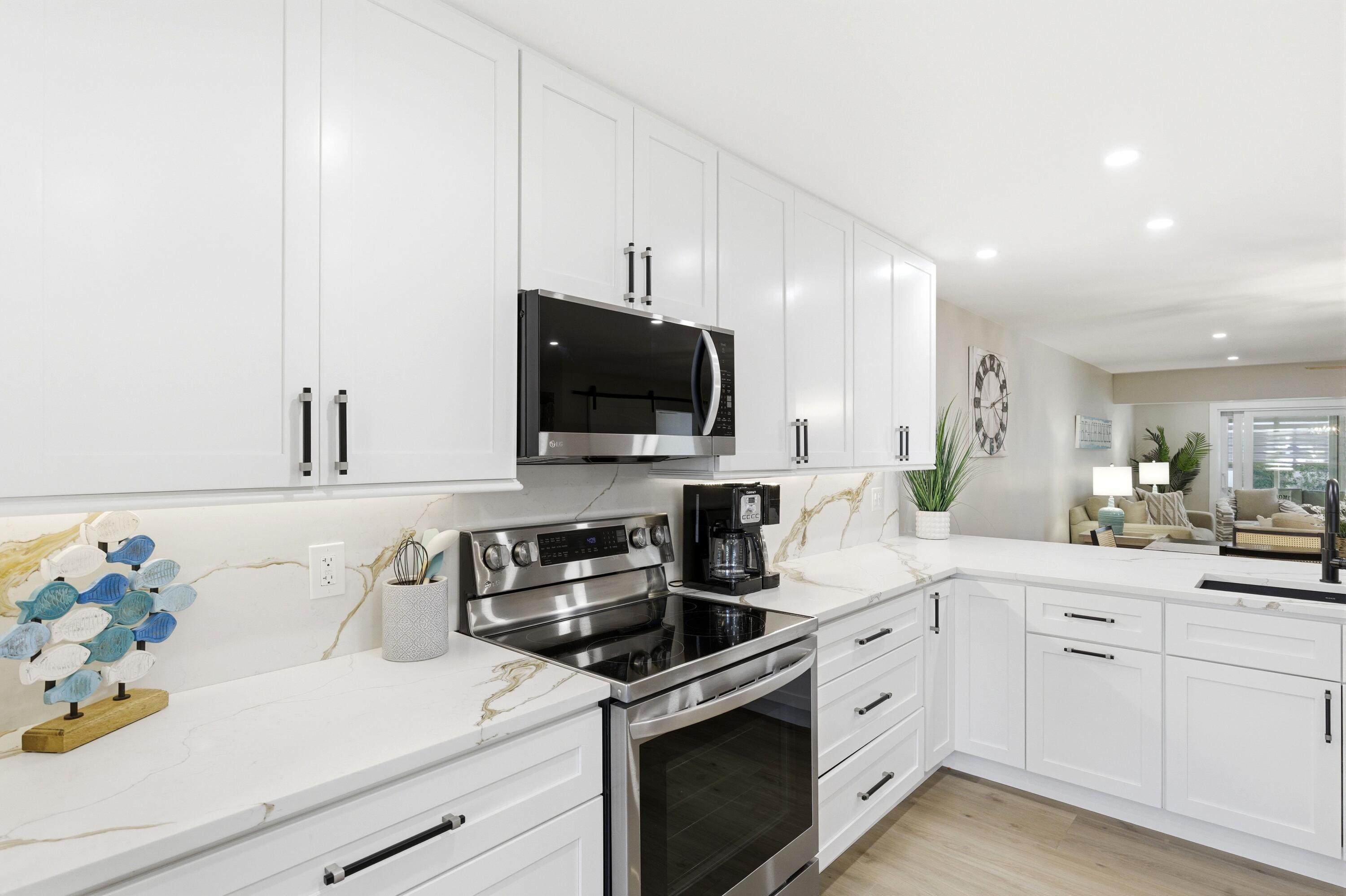 1415 Southwest 27th Avenue, Unit 104 Delray Beach, FL 33445 - Photo 5 of 43 a kitchen with a sink stove and microwave