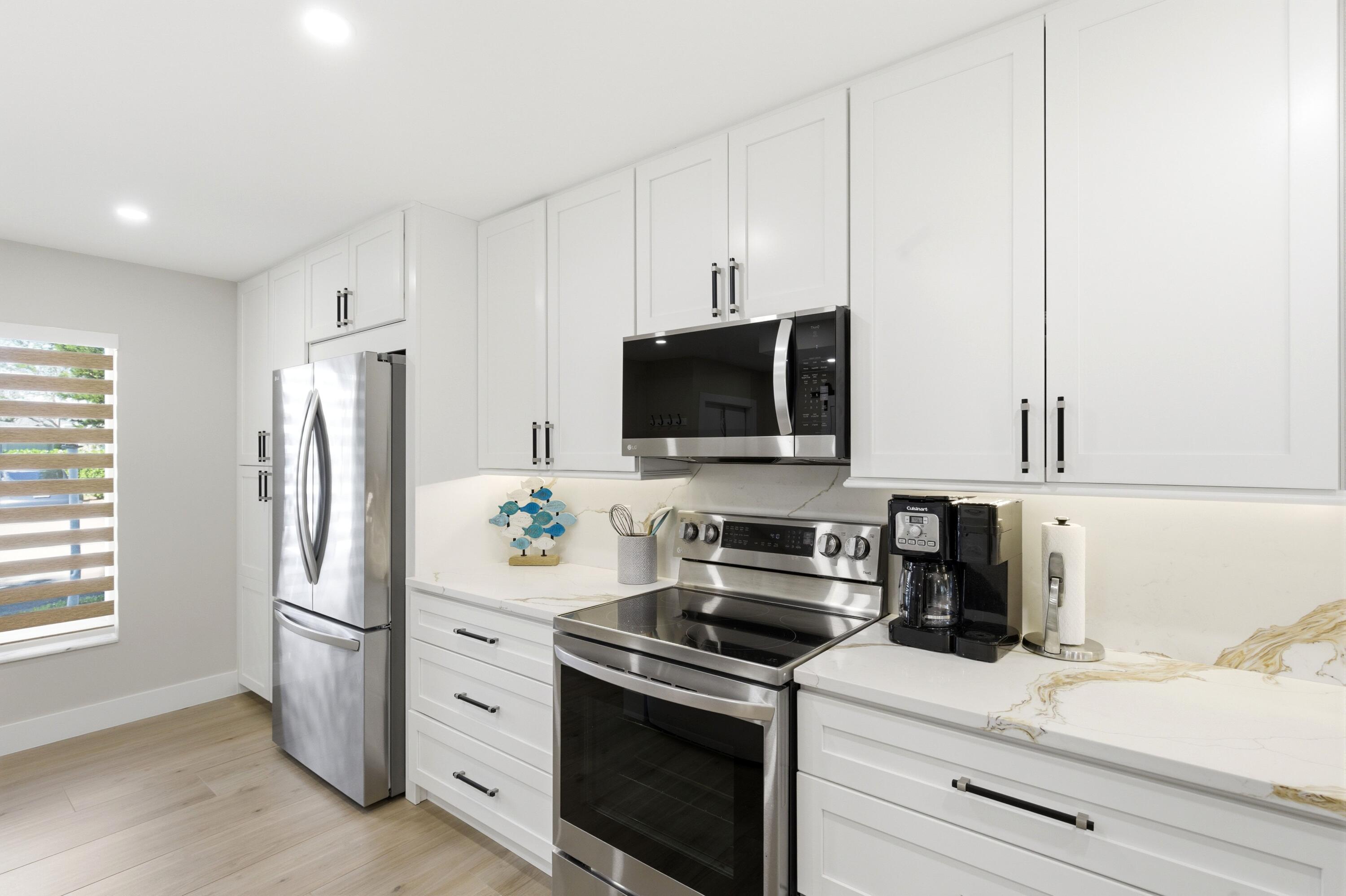 1415 Southwest 27th Avenue, Unit 104 Delray Beach, FL 33445 - Photo 6 of 43 a kitchen with stainless steel appliances a refrigerator stove and microwave