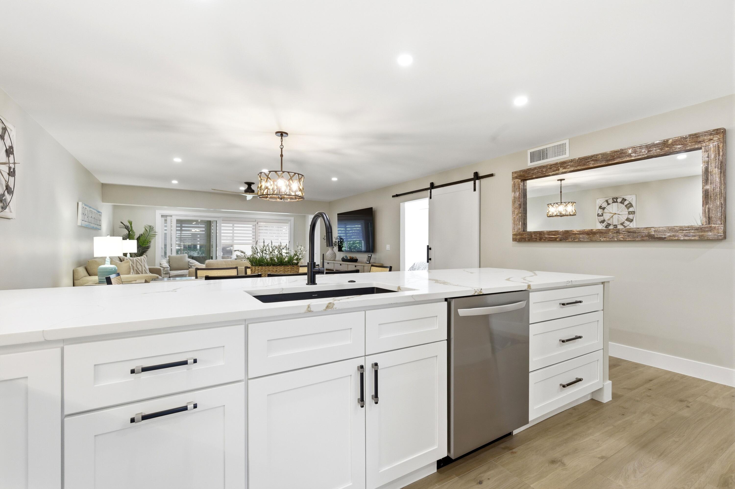 1415 Southwest 27th Avenue, Unit 104 Delray Beach, FL 33445 - Photo 7 of 43 a kitchen with cabinets stainless steel appliances and a chandelier