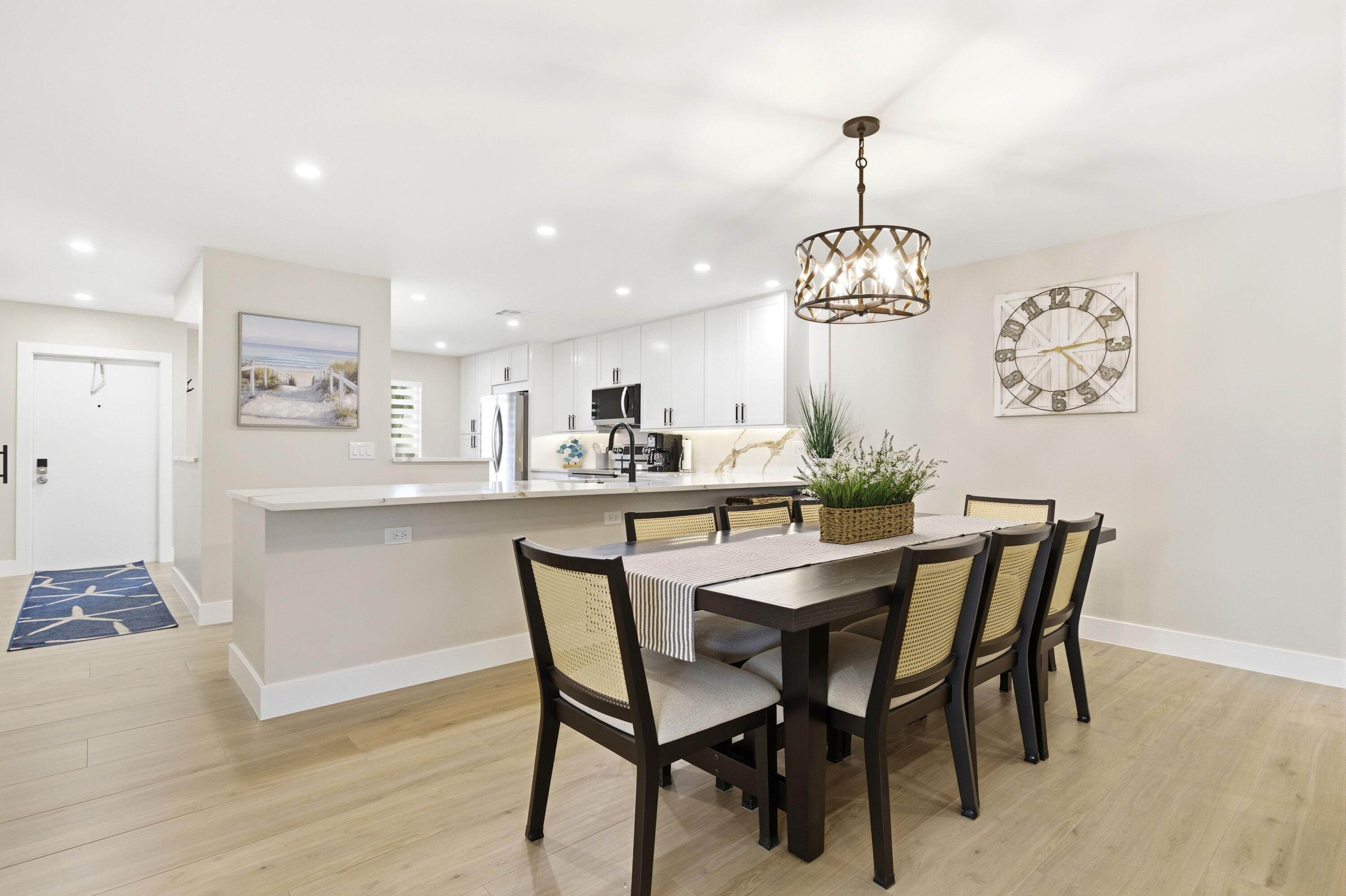 1415 Southwest 27th Avenue, Unit 104 Delray Beach, FL 33445 - Photo 9 of 43 a dining room with wooden floor a chandelier a wooden table and chairs