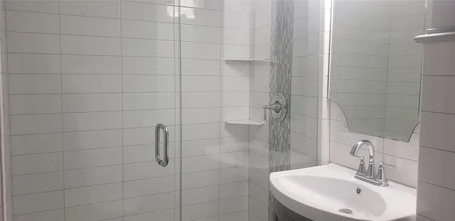 a bathroom with a sink shower and a mirror