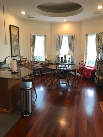 a living room with couches chairs and kitchen view with wooden floor
