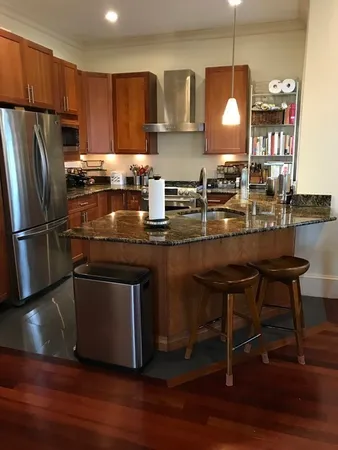 a kitchen with kitchen island granite countertop a sink cabinets and stainless steel appliances