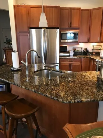 a kitchen with stainless steel appliances granite countertop a sink refrigerator and microwave