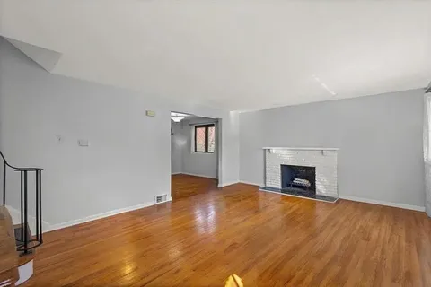 a view of empty room with wooden floor and fireplace