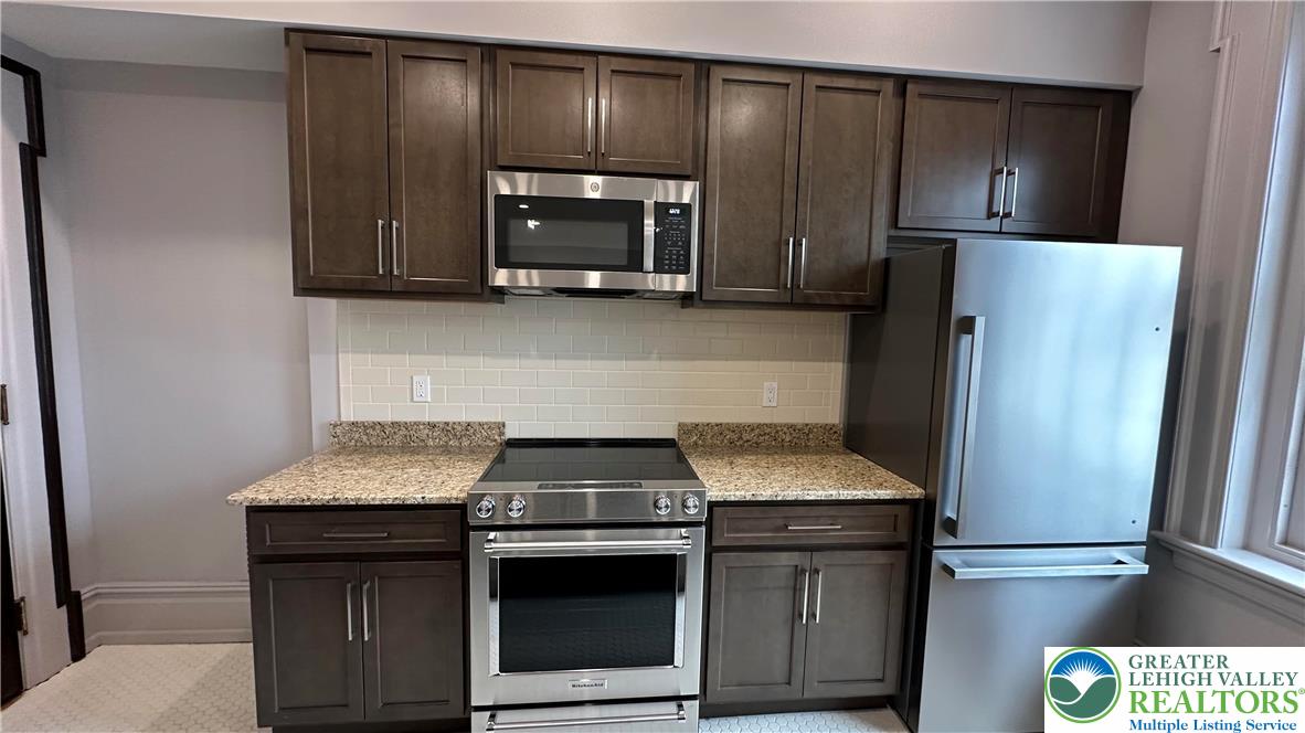 214 Spring Garden Street, Unit 3A Easton, PA 18042 - Photo 11 of 20 a kitchen with granite countertop stainless steel appliances and wooden cabinets