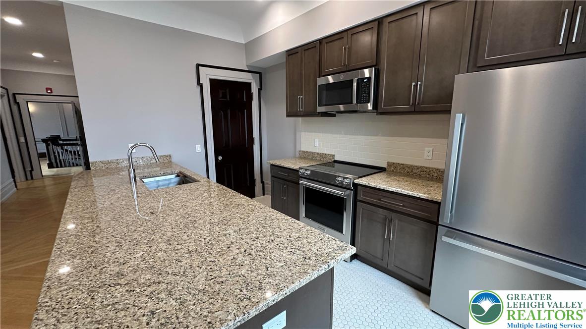 214 Spring Garden Street, Unit 3A Easton, PA 18042 - Photo 8 of 20 a kitchen with stainless steel appliances granite countertop a refrigerator stove and microwave